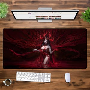 Puede incluir: Un rat&oacute;n de ordenador rojo y negro con una ilustraci&oacute;n de fantas&iacute;a de una mujer con cuernos y un vestido rojo fluido. La mujer est&aacute; de pie en un charco de l&iacute;quido rojo.