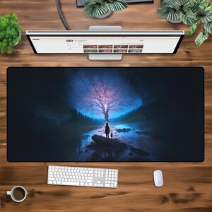 May include: A dark blue and black mouse mat with a fantasy landscape featuring a glowing tree and a lone figure standing in the foreground.