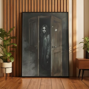 May include: A framed artwork depicts a young person standing in a doorway. The artwork is in grayscale, with the person wearing a long dress and appearing in a dimly lit room. The wooden door is slightly ajar, adding to the mysterious atmosphere.