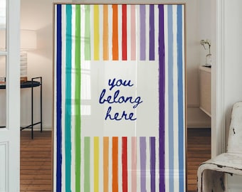 May include: A framed art print with a colorful rainbow stripe design. The artwork features vertical stripes in various colors, including red, orange, yellow, green, blue, and purple. The text "you belong here" is centered on a white square.