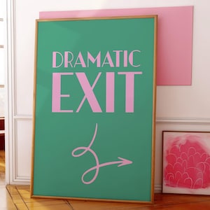 May include: A gold framed poster with a green background and pink text that reads "Dramatic Exit" with a pink arrow pointing to the right.