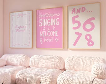 May include: A light pink living room with three framed posters and a modular sofa. The posters have text that reads "It's from a Musical", "Spontaneous Singing is Welcome here!", and "AND... 56 78". The sofa is made of a textured, light pink fabric.