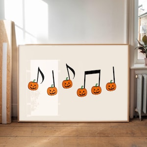 以下が含まれることがあります： カボチャを音符の頭にした楽譜が描かれた額入りのプリント。カボチャはオレンジ色で、顔が彫られており、緑色の茎が付いています。背景は薄いベージュ色で、フレームは薄い茶色です。