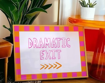 May include: A gold framed sign with a white background and pink and orange checkered border. The sign says "Dramatic Exit" in pink lettering with a gold arrow pointing to the right.
