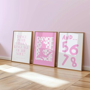 May include: Three framed art prints with wooden frames. The prints feature pink and white text and graphics related to dance. One print reads "Dance is the hidden language of the soul." Another says "Dance" repeatedly.