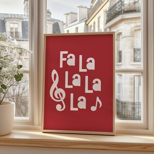 May include: A red framed print with white text that reads "Fa La La La La" with a treble clef and a musical note.