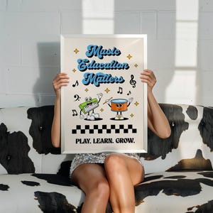 May include: A white framed poster with the text "Music Education Matters" in blue and yellow lettering. The poster features a cartoon keyboard and drum playing music. The text "Play. Learn. Grow." is at the bottom of the poster.