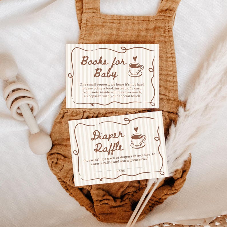May include: Two baby shower cards with text: "Books for Baby" and "Diaper Raffle." The cards have a striped background and a coffee cup illustration. The cards are on a brown onesie.