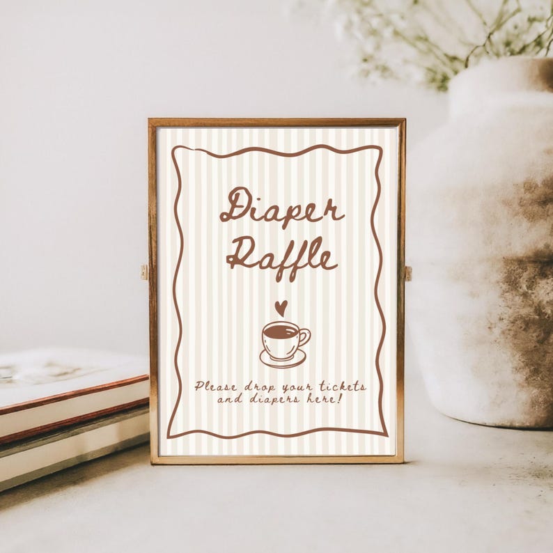 May include: A framed sign with the words "Diaper Raffle" in brown script. The sign has a striped background and a brown border. Below the text is a small coffee cup illustration with a heart above it. The text "Please drop your tickets and diapers here!" is at the bottom.