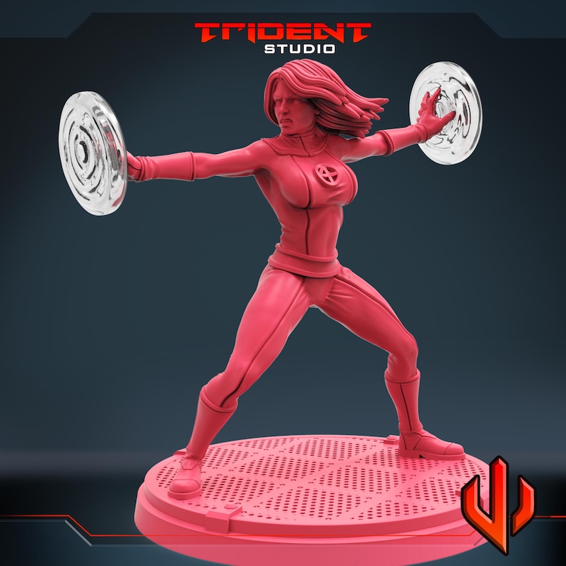 May include: A red figurine of a female superhero in a dynamic pose, holding two transparent circular shields. She wears a form-fitting suit and stands on a circular base. The Trident Studio logo is visible at the top.