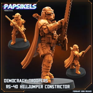 Puede incluir: Figuras en miniatura de color naranja de los Democracy Troopers, el RS-40 Helljumper Constrictor. Las figuras están en posición de combate, sosteniendo armas. Las figuras están sobre bases negras. El texto "Papsikels" y "February 2026 Release" son visibles.