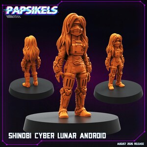 May include: An orange monochrome miniature figure of a Shinobi Cyber Lunar Android with long hair, a face mask, and tactical gear. The figure is displayed from three angles on black circular bases, with the text PAPSIKELS and SHINOBI CYBER LUNAR ANDROID.