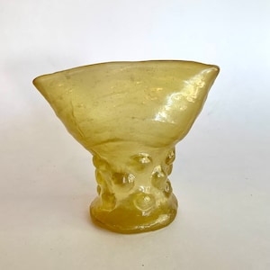 May include: A yellow glass vase with a wide, shallow bowl and a textured, bulbous base.