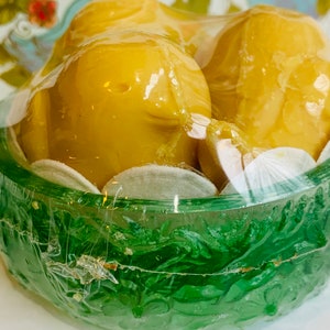 Puede incluir: Dos jabones amarillos con forma de p&aacute;jaro en un nido de pl&aacute;stico verde con un dise&ntilde;o floral blanco. Los jabones est&aacute;n envueltos en pl&aacute;stico transparente.