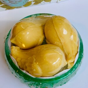 Puede incluir: Tres jabones amarillos con forma de p&aacute;jaro en un recipiente verde. Los jabones est&aacute;n dispuestos en forma de nido.