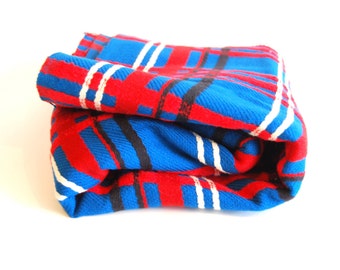 May include: A rolled up blue and red plaid blanket with white and black stripes.