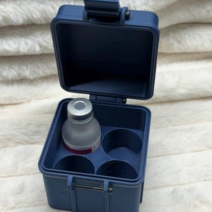 May include: A dark blue, square, hinged storage case with a latch, featuring four circular interior compartments. One compartment holds a small, translucent glass vial with a silver cap and a label with the visible text BACTERIOSTATIC.