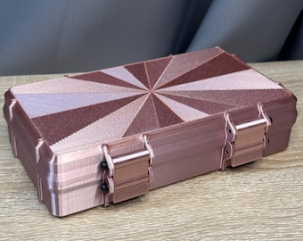 May include: A rectangular rose gold storage case with a sunburst pattern on the lid. The case features a textured finish, two hinged latches on the front, and a structured design with visible layer lines from the 3D printing process.