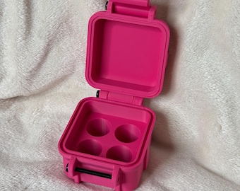 May include: A bright pink, small, square-shaped, plastic container with a hinged lid. The container has four circular compartments inside.