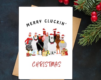May include: A white Christmas card with the text "MERRY CLUCKIN' CHRISTMAS" in black and red. The card features a cartoon illustration of chickens wearing Santa hats and festive decorations. The card is on a brown envelope.