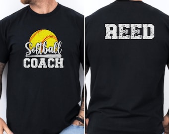 May include: A black t-shirt featuring a yellow softball graphic with a bat and the text Softball COACH on the front. The back of the shirt displays the name REED in large, distressed white block lettering across the upper back area.
