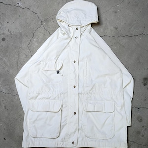 May include: An off-white hooded jacket featuring a front button placket, a drawstring hood, and four front pockets. The jacket includes two large lower patch pockets with flaps and two smaller upper chest pockets, one of which has a flap.