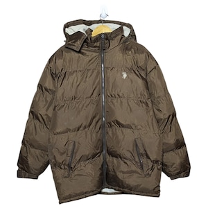 May include: Brown puffer jacket with a hood and a full-length zip. The jacket has a small logo on the chest and two front pockets. The jacket is hanging against a white background. This outerwear is designed for cold weather.