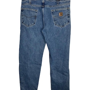 May include: A pair of blue denim jeans with a brown leather patch on the back pocket. The jeans have a straight leg and a relaxed fit.