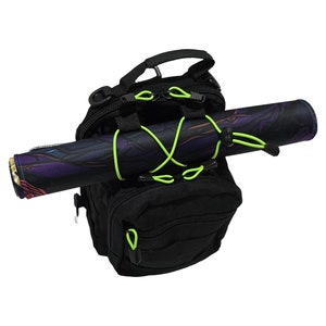 May include: Black tactical backpack with a rolled-up mat secured by neon green bungee cords. The mat features a colorful, abstract design. The backpack has multiple compartments and a top handle.