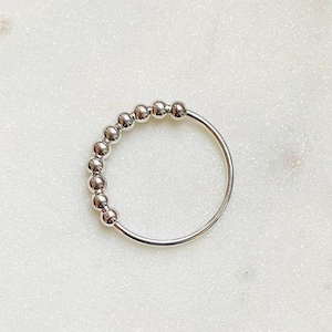 Könnte beinhalten: Ein silberner Ring mit einer Reihe kleiner, runder Perlen.