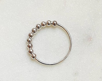 May include: A silver ring with a row of small, round beads.