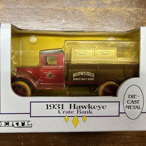 May include: A red 1931 Hawkeye Crate Bank die-cast metal toy truck with a Budweiser Barley Malt Syrup logo and two yellow boxes that say "Anheuser-Busch Yeast".