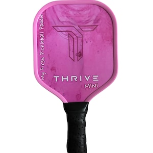 May include: Pink pickleball paddle with a black handle and the text "THRIVE MINI" and "My First Pickleball Paddle" printed on the paddle face.