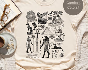May include: A cream colored t-shirt with a black and white print of various Egyptian symbols and hieroglyphics. The text "Comfort Colors®" is printed in the top right corner of the shirt.