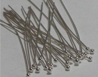May include: A pile of silver-colored head pins with round heads. The pins are about 1 inch long.