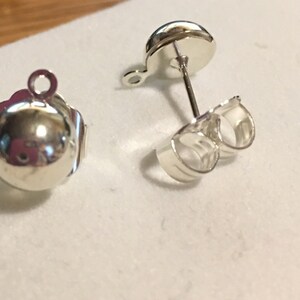 May include: Two silver earring posts with a loop on one end and a post with a butterfly back on the other end.