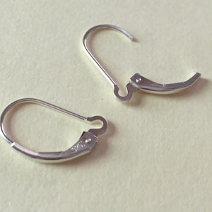 May include: Two silver earring hooks with a curved design. The hooks are made of metal and have a smooth finish.