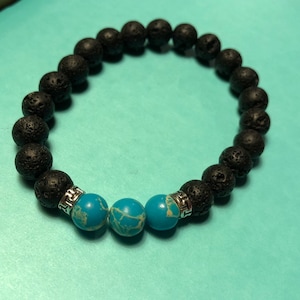 May include: Black lava rock beaded bracelet with three turquoise blue gemstone beads and silver spacers.
