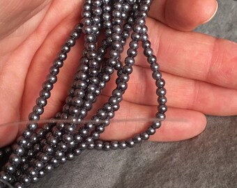May include: A strand of gray pearl beads. The beads are small and round, and they are strung on a clear thread.
