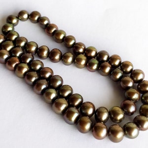 May include: A strand of iridescent brown pearls. The pearls are round and smooth, with a slight sheen. The pearls are strung on a clear thread.