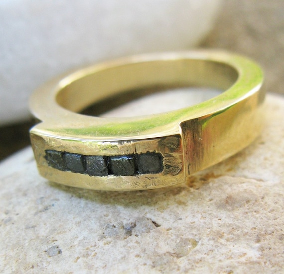 Five black diamonds in the rough on gold ring