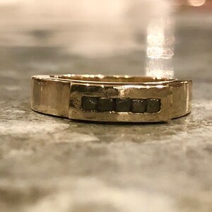 以下が含まれることがあります： 中央に小さな暗い灰色の石が並んだ金のバンド
