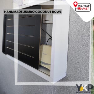 May include: A white wooden cabinet with a black sliding door. The cabinet is mounted on a grey wall and contains a router. The text "HANDMADE JUMBO COCONUT BOWL" is displayed on the cabinet.