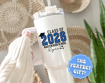 May include: White tumbler with a handle, featuring the text "CLASS OF 2026" in blue, "MARTIN HIGH SCHOOL", and a soccer ball graphic. The name "Ryan" is also printed on the tumbler. A blue and white sticker says "THE PERFECT GIFT!"