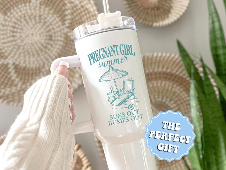 May include: White tumbler with a teal design that says "Pregnant Girl Summer 2023 Suns Out Bumps Out". The tumbler has a lid and a straw. The text "The Perfect Gift" is in a blue circle.