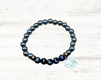 Könnte beinhalten: Ein silbernes Perlenarmband mit einem schwarzen Anhänger, auf dem "BILLY" steht, und einem silbernen Pfotenabdruck-Anhänger mit einem Herz.
