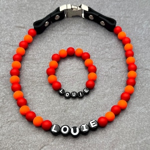 Puede incluir: Un collar y un brazalete a juego de cuentas rojas y naranjas con el nombre "LOUIE" escrito en cuentas negras.