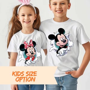 A young girl and boy are standing next to each other, both wearing white t-shirts with cartoon characters on them.