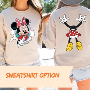 The image is a collage of two images, one showing the front of a white sweatshirt with Minnie Mouse and the other showing the back of the same sweatshirt with Minnie Mouse's arms and legs raised.