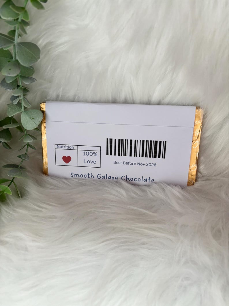 May include: A wrapped chocolate bar with a white label featuring a barcode and the text "Best Before Nov 2026." The label also includes a heart symbol and the words "100% Love." The words "Smooth Galaxy Chocolate" are printed at the bottom.